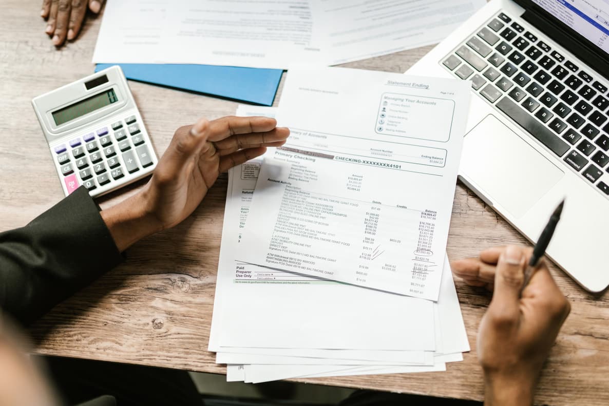 Financial records and bank statements being examined with a calculator and laptop